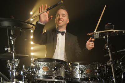 Un groupe de musiciens et une chanteuse se produisent sur scène sous des lumières colorées.