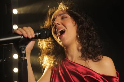 Un groupe de musiciens et une chanteuse se produisent sur scène sous des lumières colorées.