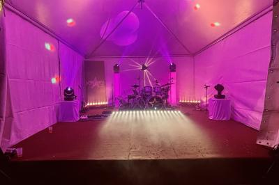 Un groupe de musiciens et une chanteuse se produisent sur scène sous des lumières colorées.