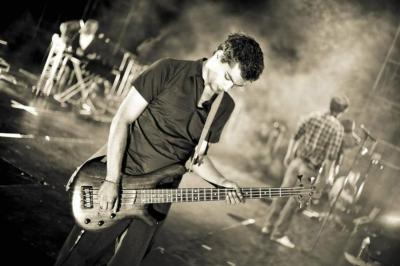 Un groupe de musiciens et une chanteuse se produisent sur scène sous des lumières colorées.