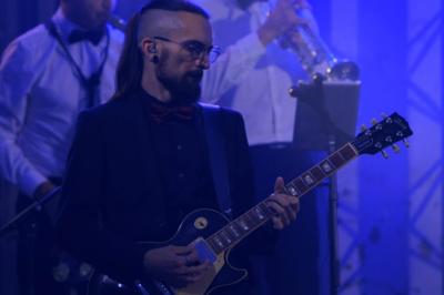 Un groupe de musiciens et une chanteuse se produisent sur scène sous des lumières colorées.