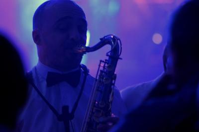 Un groupe de musiciens et une chanteuse se produisent sur scène sous des lumières colorées.