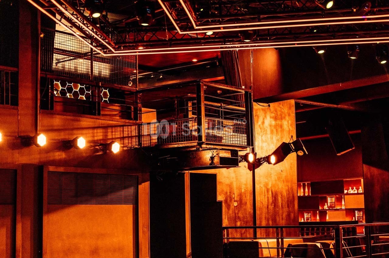 Salle de spectacle avec éclairage chaleureux, balcons métalliques et décorations en bois et métal.