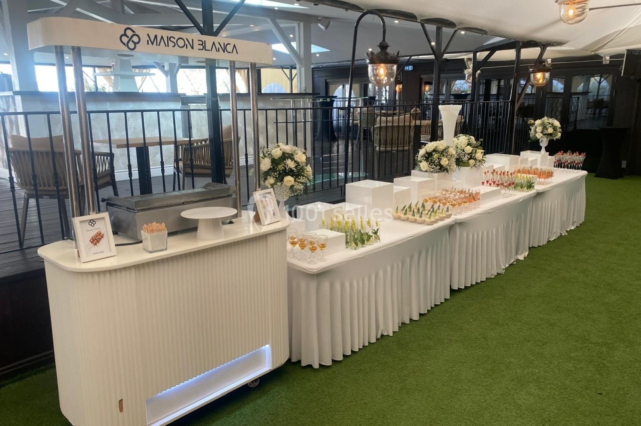Buffet élégant avec verrines et décorations florales, installé sur une pelouse sous une tente lumineuse.