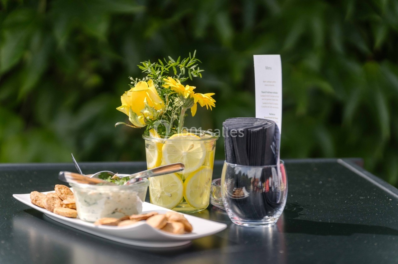 Assiette de crackers avec une sauce, accompagnée d'un vase de fleurs jaunes et d'un verre contenant des serviettes noires.