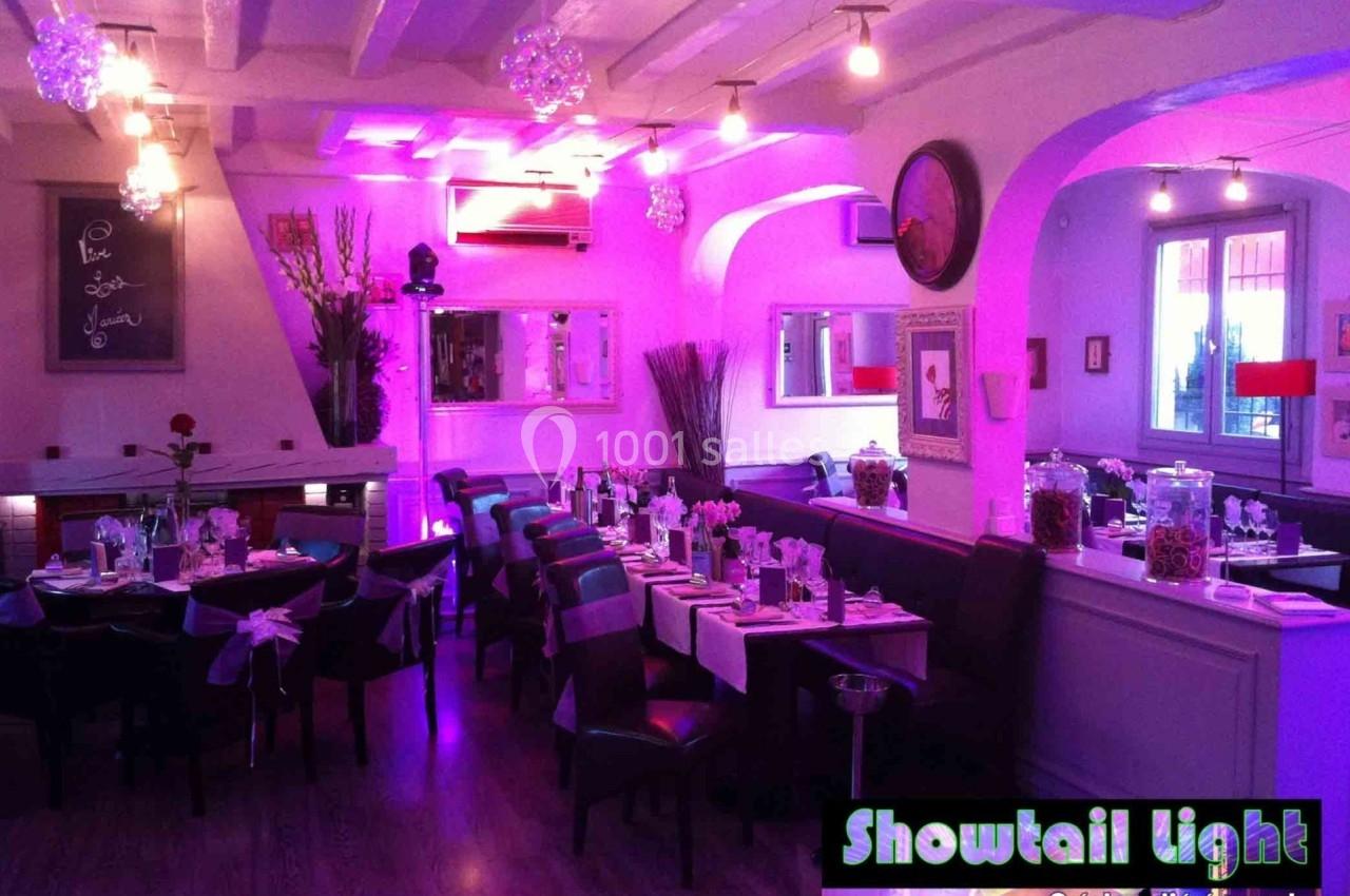 Salle de réception décorée avec des tables dressées, éclairage violet et ambiance chaleureuse.