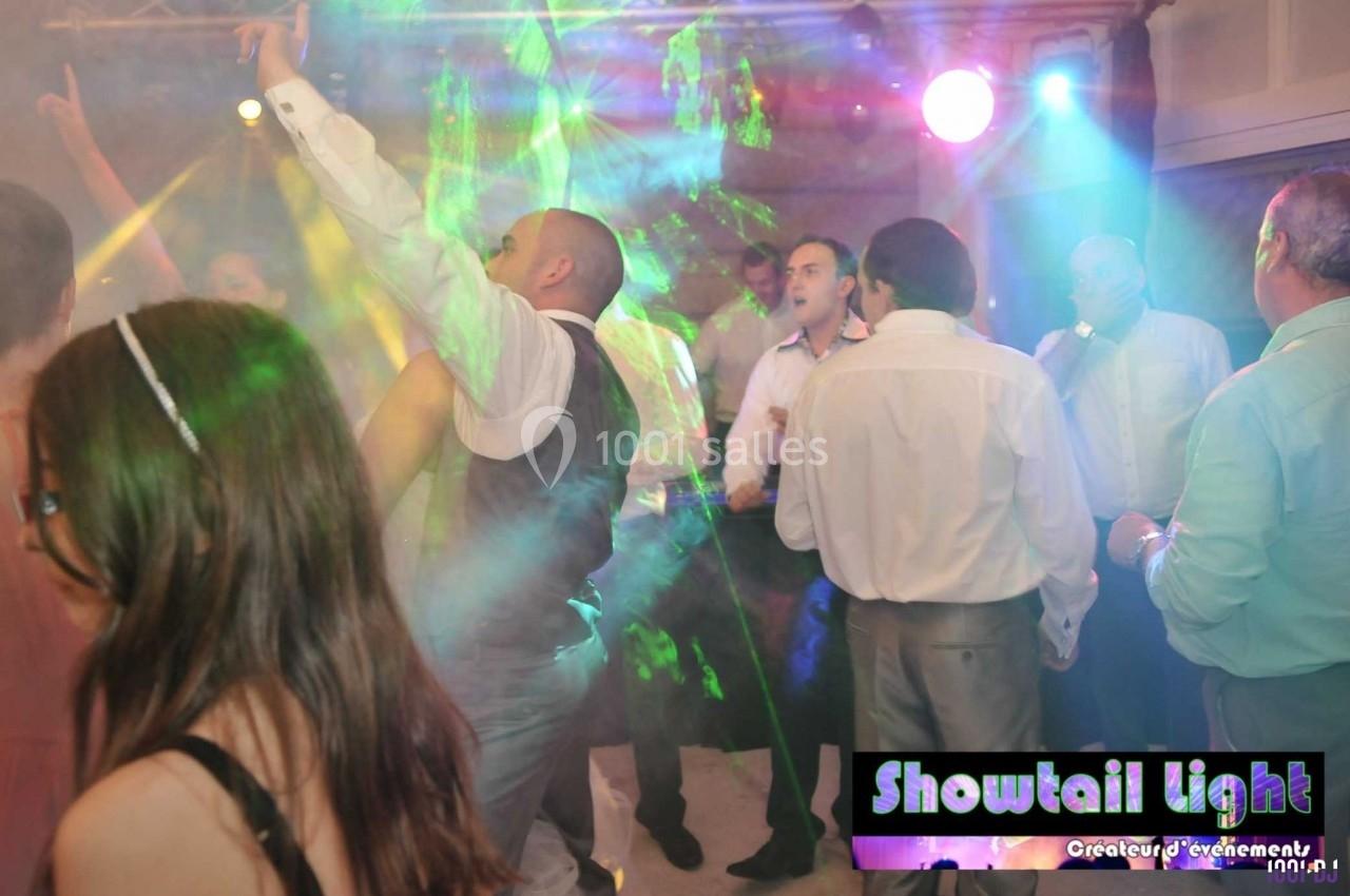 Des personnes dansent sous des lumières colorées dans une ambiance festive en intérieur.