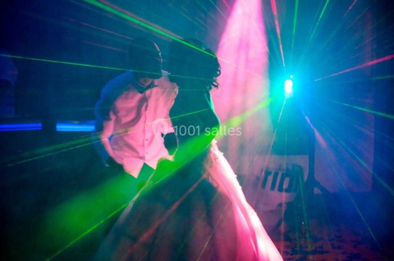 Un couple danse sous des lumières colorées et des effets laser dans une ambiance festive.