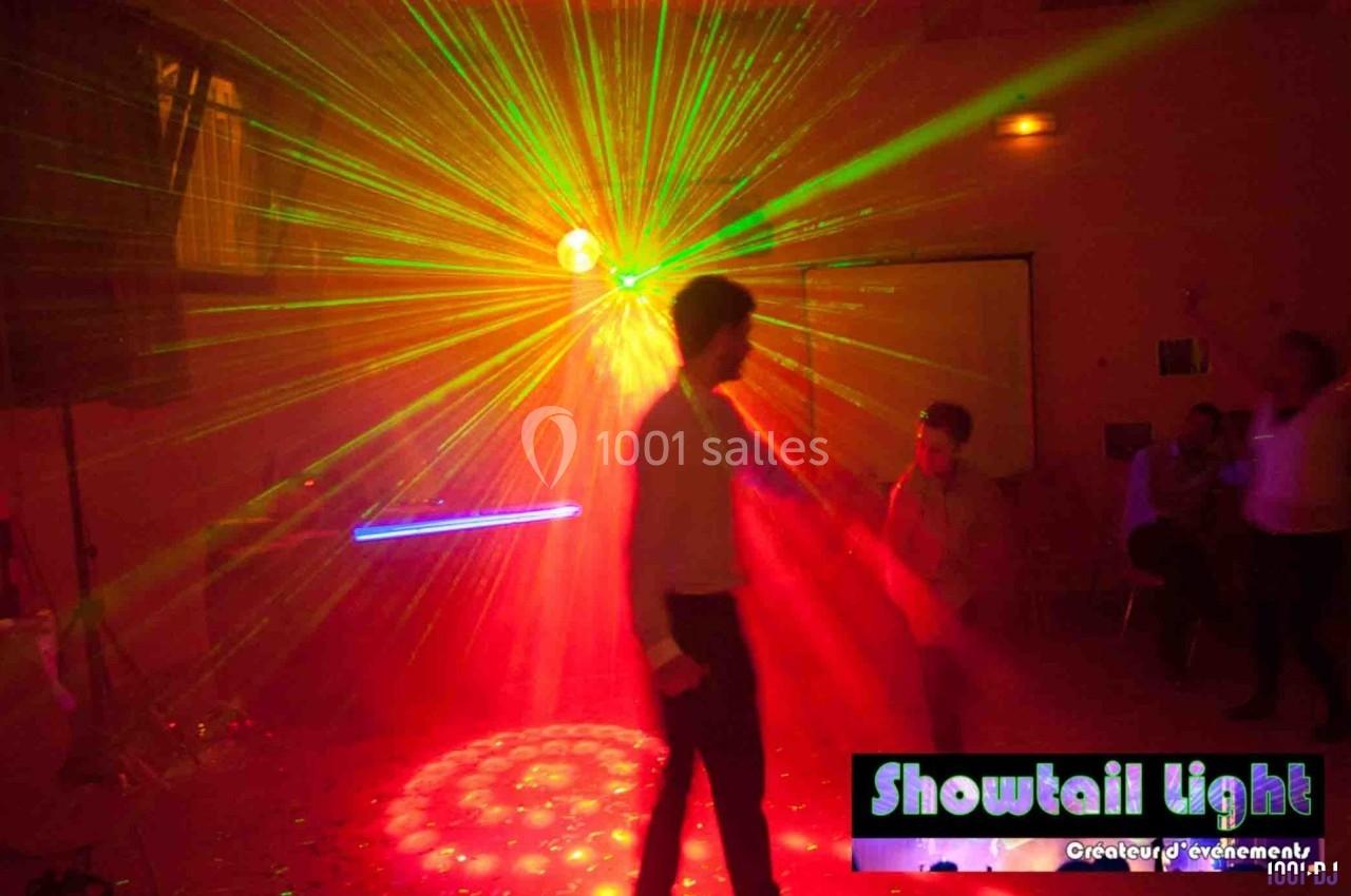 Un homme danse sous des lumières laser multicolores dans une salle sombre lors d'un événement festif.
