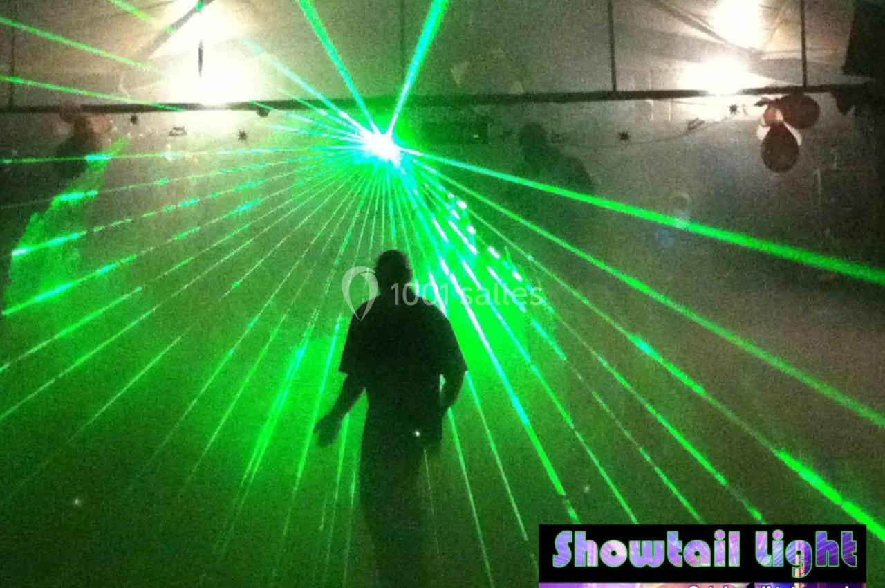 Un homme debout dans une salle sombre éclairée par des faisceaux laser verts.
