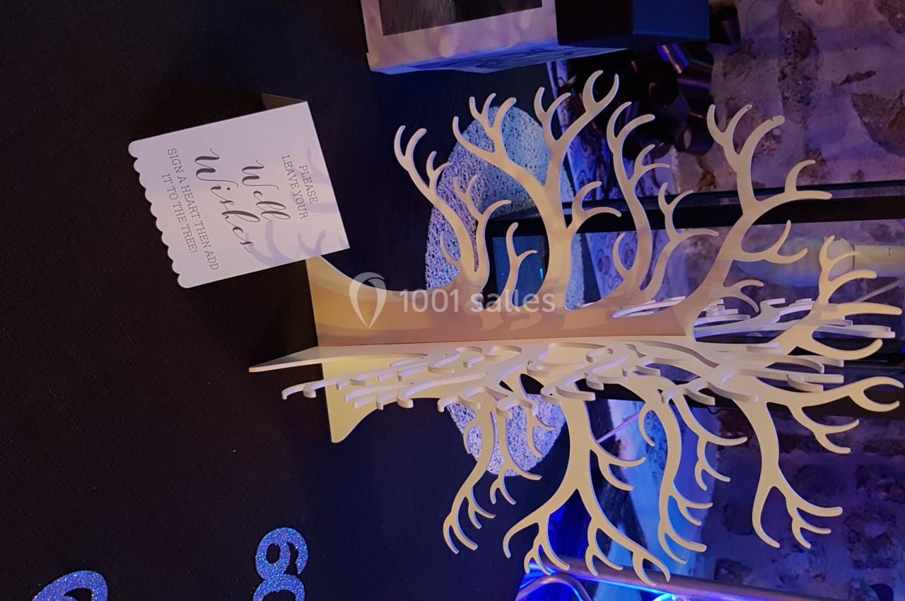 Arbre décoratif en bois blanc sur une table sombre, accompagné d'une carte avec un message imprimé.