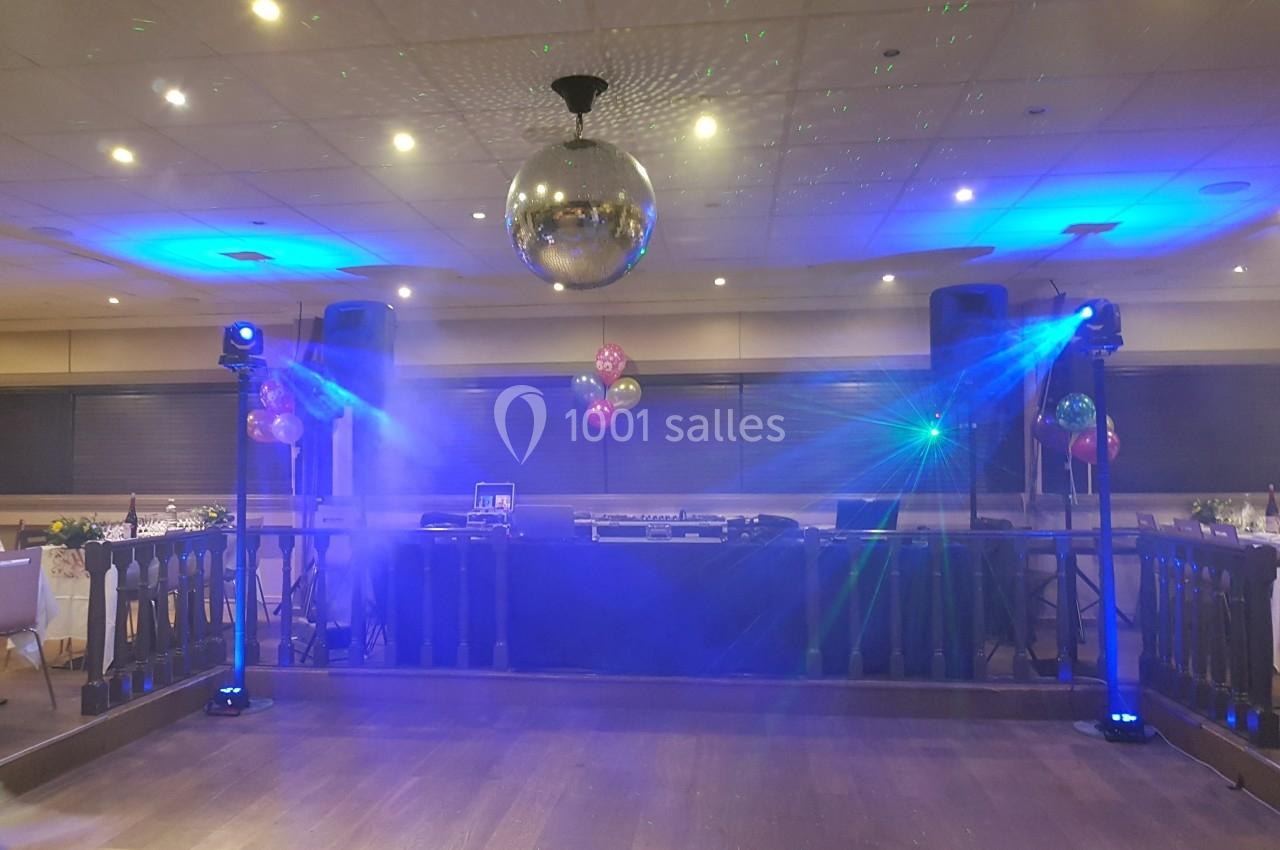 Salle de réception avec piste de danse, éclairages colorés, boule disco et équipement de sonorisation.