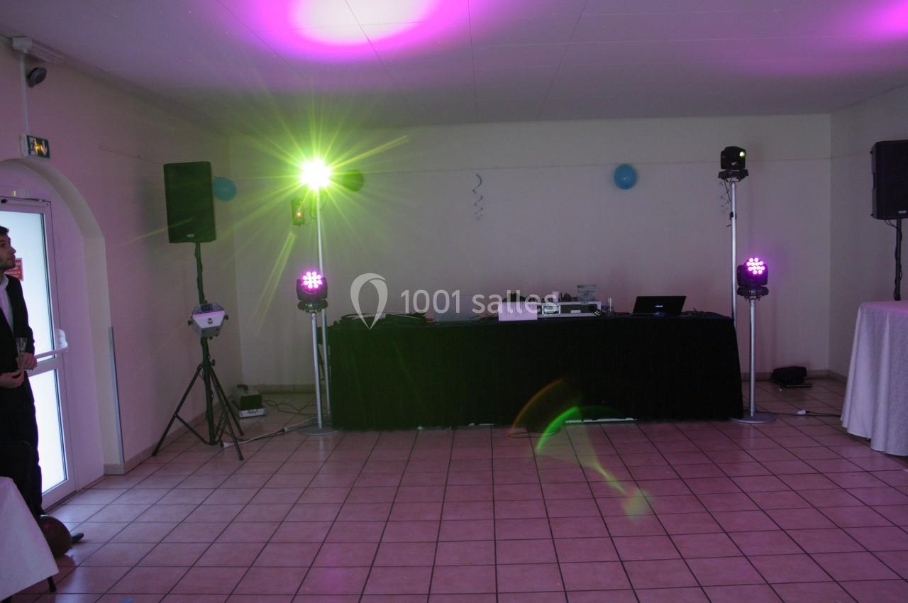 Salle de réception avec éclairage coloré et équipement de sonorisation installé sur une scène.