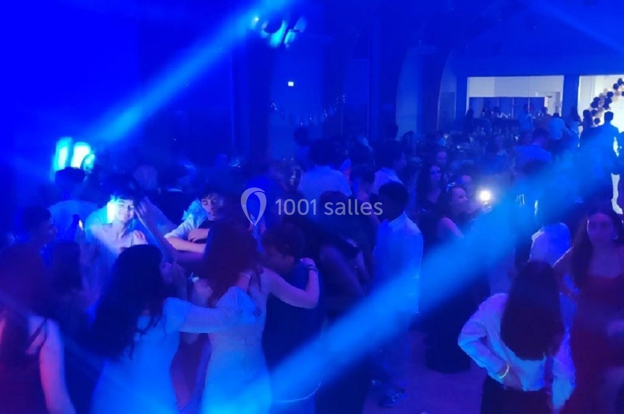 Groupe de personnes dansant dans une salle éclairée par des lumières bleues, ambiance festive.