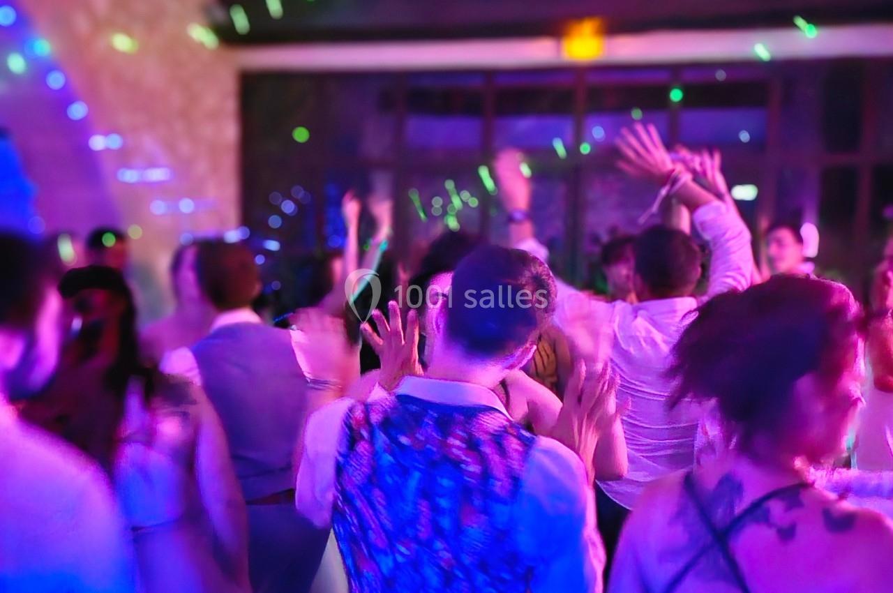 Personnes dansant dans une ambiance festive avec éclairages colorés et musique en arrière-plan.