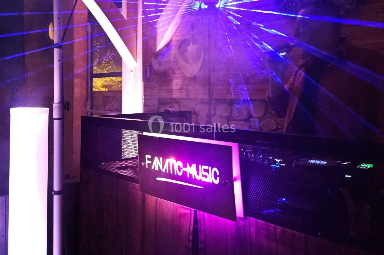 Panneau lumineux ’F.ANTIC MUSIC’ suspendu devant une scène avec des effets de lumière violette et bleue.