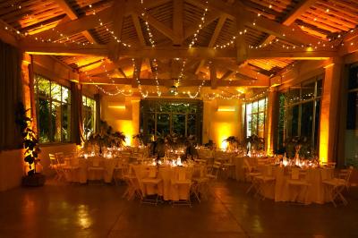 Table décorée avec des bougies allumées en premier plan, devant une fontaine éclairée et une réception en soirée.