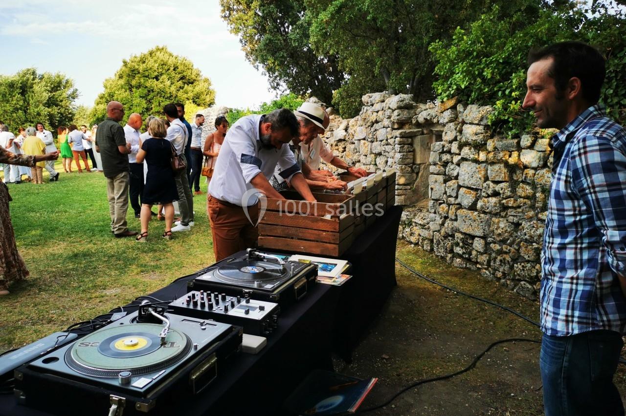 Des personnes participent à un événement en plein air près d'une table avec des platines vinyles et des caisses en bois.