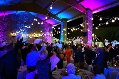 Table décorée avec des bougies allumées en premier plan, devant une fontaine éclairée et une réception en soirée.