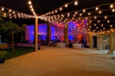Table décorée avec des bougies allumées en premier plan, devant une fontaine éclairée et une réception en soirée.