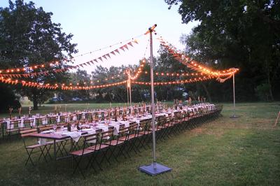 Table décorée avec des bougies allumées en premier plan, devant une fontaine éclairée et une réception en soirée.