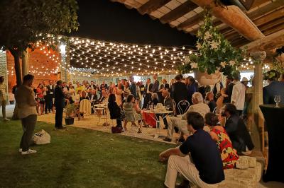 Table décorée avec des bougies allumées en premier plan, devant une fontaine éclairée et une réception en soirée.