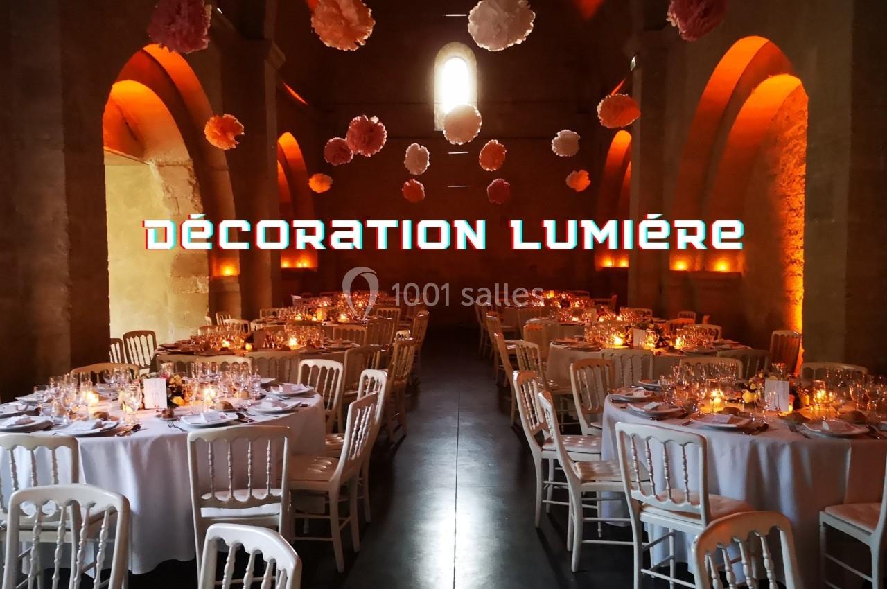 Salle de réception décorée avec des tables rondes, éclairage chaleureux et suspensions florales au plafond.