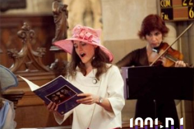 Miniature Chanteuse cérémonie Une violoncelliste joue lors d'une cérémonie dans une église, entourée d'invités debout et de mariés à l'arrière-plan.