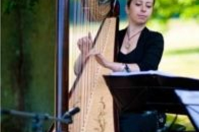 Miniature Harpe Une violoncelliste joue lors d'une cérémonie dans une église, entourée d'invités debout et de mariés à l'arrière-plan.