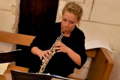 Miniature Hautbois Une violoncelliste joue lors d'une cérémonie dans une église, entourée d'invités debout et de mariés à l'arrière-plan.