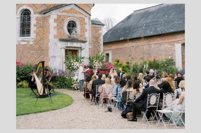 Miniature Cérémonie laïque Une violoncelliste joue lors d'une cérémonie dans une église, entourée d'invités debout et de mariés à l'arrière-plan.