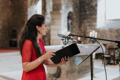 Miniature Chanteuse Une violoncelliste joue lors d'une cérémonie dans une église, entourée d'invités debout et de mariés à l'arrière-plan.