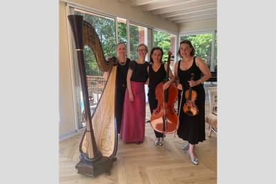 Miniature Concert privé Quatuor Une violoncelliste joue lors d'une cérémonie dans une église, entourée d'invités debout et de mariés à l'arrière-plan.