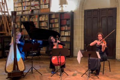Miniature Concert privé Trio Une violoncelliste joue lors d'une cérémonie dans une église, entourée d'invités debout et de mariés à l'arrière-plan.