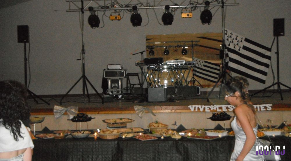 Buffet garni de plats variés devant une scène équipée de matériel de sonorisation et éclairée par des projecteurs.