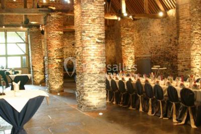 Miniature Location salle Court-Saint-Étienne (Brabant wallon) - Ferme de Beaurieux #2 Charpente en bois apparente d'un bâtiment ancien avec des murs en briques et un éclairage intérieur chaleureux.