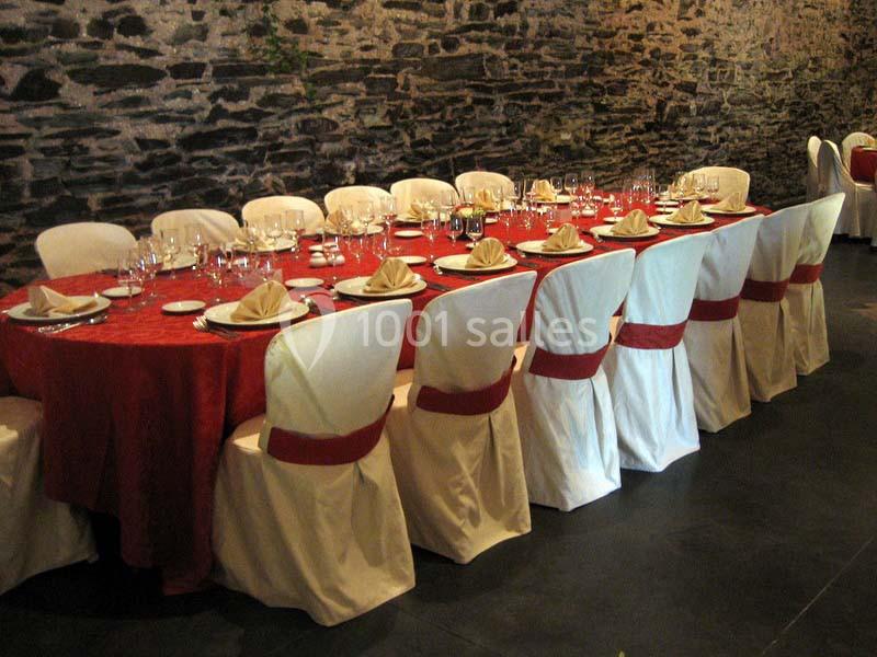 Location salle Court-Saint-Étienne (Brabant wallon) - Ferme de Beaurieux #3 Table dressée avec une nappe rouge, des assiettes, des verres et des serviettes pliées, entourée de chaises blanches.