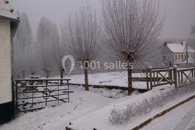 Miniature Location salle Court-Saint-Étienne (Brabant wallon) - Ferme de Beaurieux #22 Paysage hivernal avec arbres dénudés, sol enneigé, clôture en bois et maisons en arrière-plan sous un ciel gris.