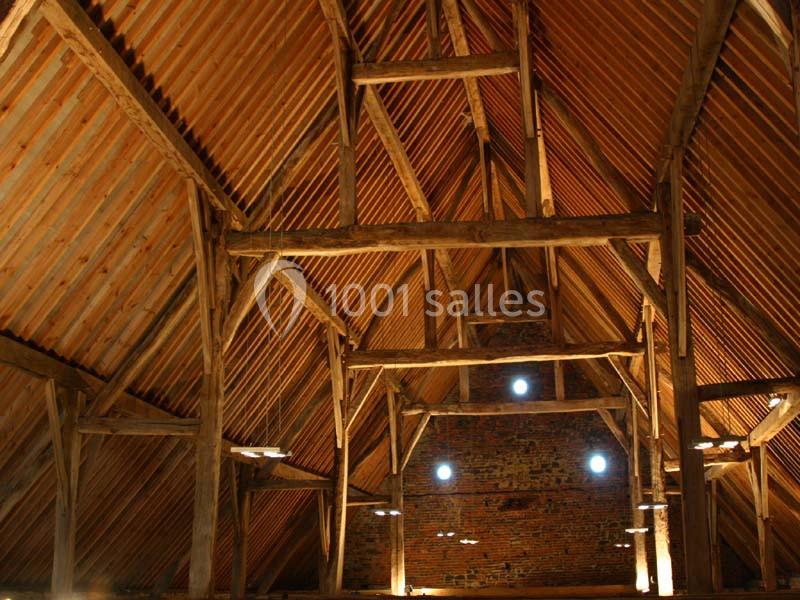 Location salle Court-Saint-Étienne (Brabant wallon) - Ferme de Beaurieux #9 Charpente en bois apparente d'un grenier ou d'une grange, avec un toit en tuiles et un mur en briques au fond.
