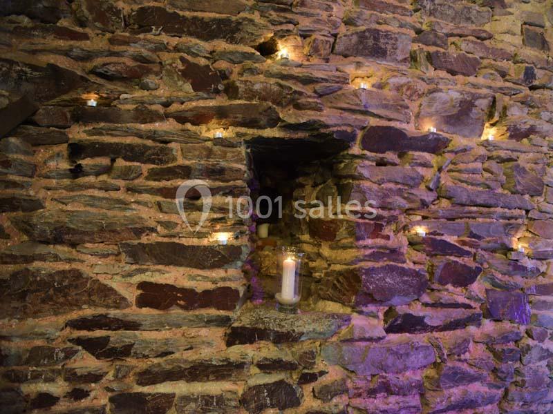 Location salle Court-Saint-Étienne (Brabant wallon) - Ferme de Beaurieux #5 Mur en pierre éclairé par des bougies, avec une niche centrale contenant une bougie allumée.