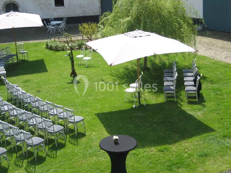 Location salle Court-Saint-Étienne (Brabant wallon) - Ferme de Beaurieux #13 Chaises disposées en extérieur sur une pelouse avec des parasols blancs, préparées pour un événement en plein air.