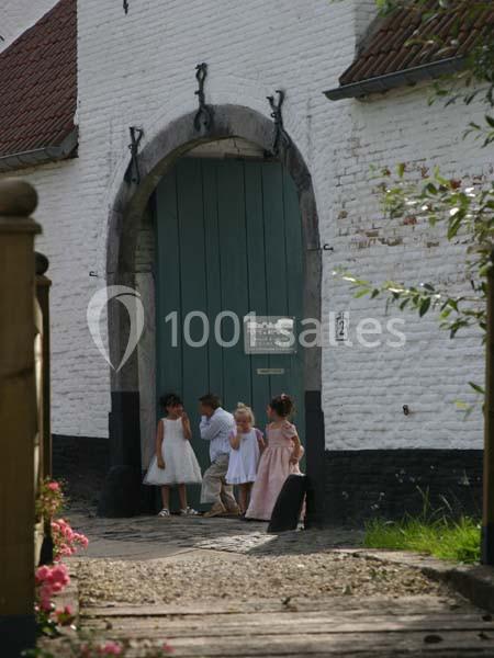 Location salle Court-Saint-Étienne (Brabant wallon) - Ferme de Beaurieux #18 Des enfants en tenue élégante entrent par une grande porte en bois vert d'un bâtiment blanc ancien.