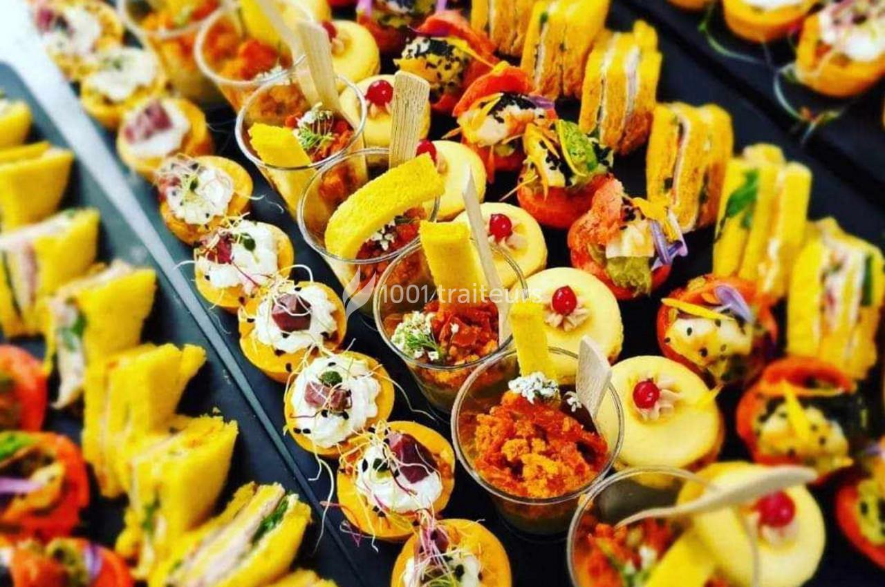 Plateau de bouchées apéritives variées comprenant verrines, mini-sandwichs, et amuse-bouches colorés.