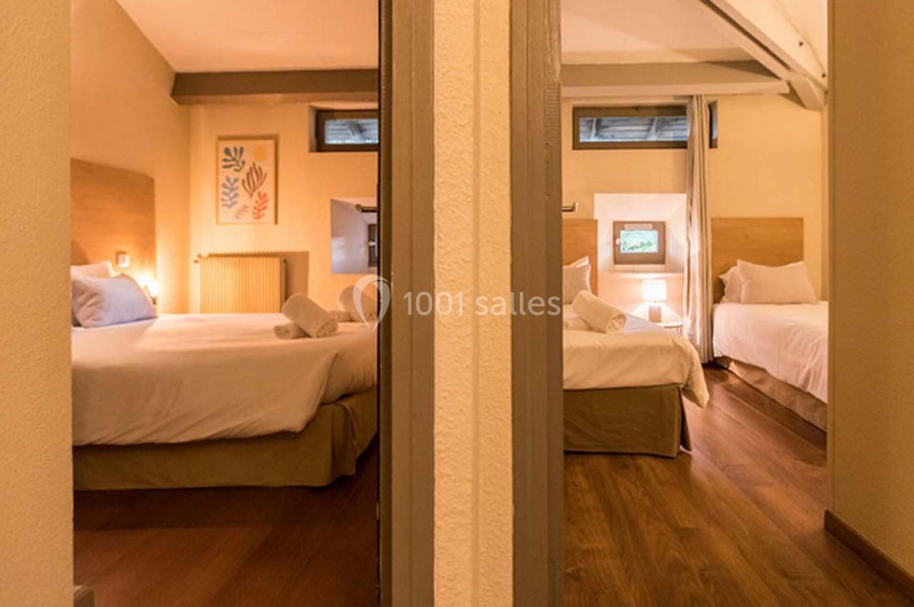 Deux chambres avec lits doubles, draps blancs, lampes de chevet allumées et parquet en bois clair.