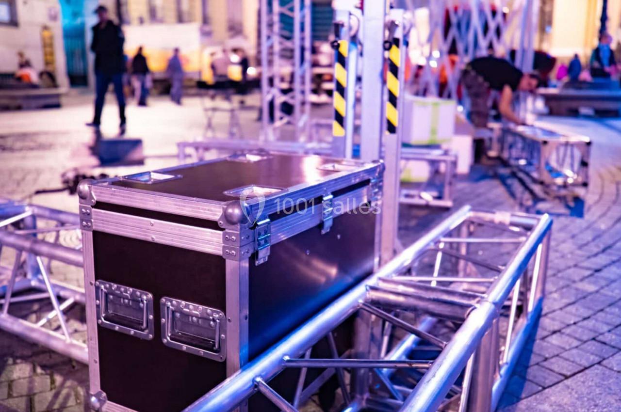 Matériel de scène avec flight case et structures métalliques installé en extérieur, éclairage nocturne.