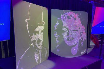 Miniature Animson #20 Portraits scintillants de deux figures célèbres réalisés en paillettes sur des panneaux noirs, exposés sur une scène.