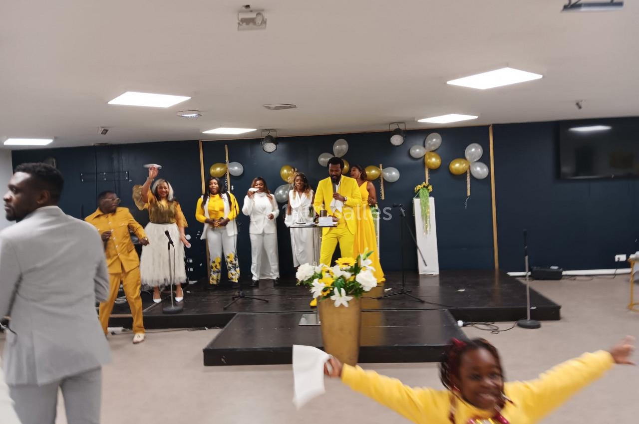 Un groupe de personnes sur une scène décorée de ballons, avec un enfant souriant au premier plan.