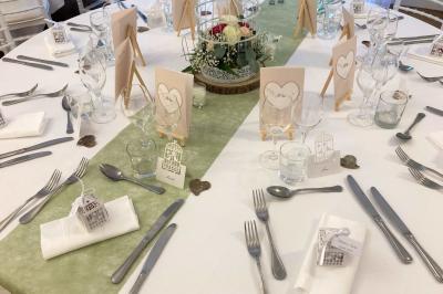 Homme concentré cuisinant en extérieur sur une plancha, entouré de végétation sous un ciel nuageux.
