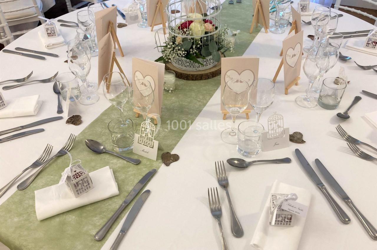 Table de réception décorée avec des éléments romantiques, nappes blanches, centres de table floraux et marque-places.