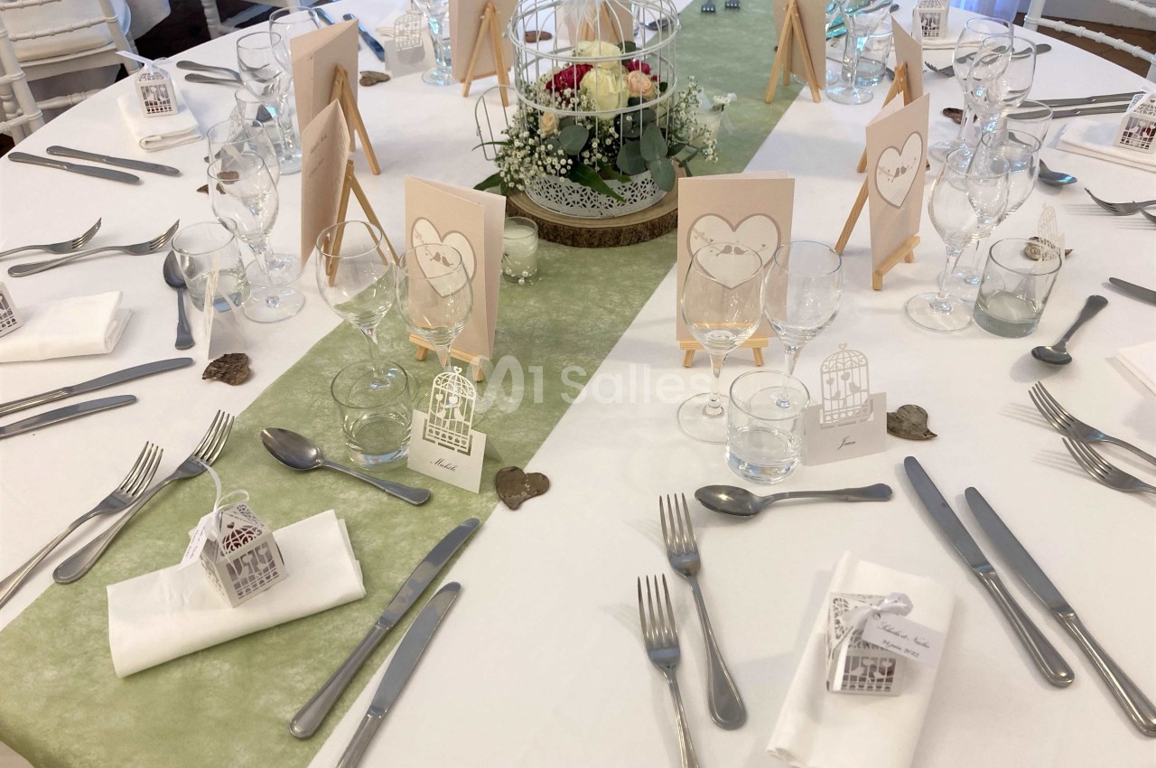 Table de réception décorée avec des éléments romantiques, nappes blanches, centres de table floraux et marque-places.
